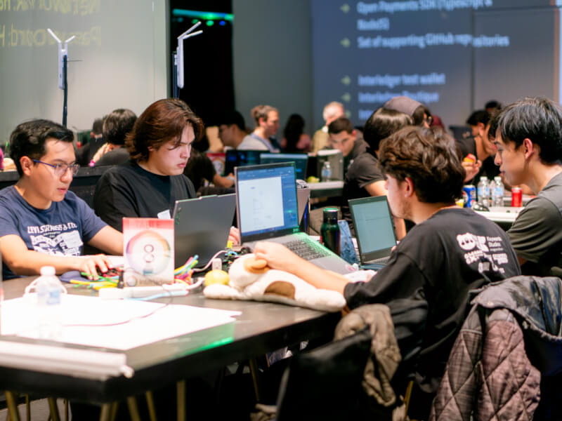 Four developers working together on laptops at a table during the Interledger Hackathon 2025.